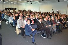 Blick in das Publikum des voll besetzten Messeraums der in Reihen gestuhlt ist.