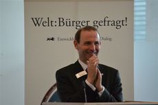 Dr. Dieter Heidtmann steht strahlend vor dem Banner Welt_Bürger gefragt.