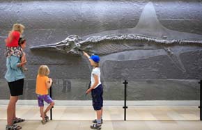 Das Bild zeigt eine Familie vor der Versteinerung eines Ichthyosaurier