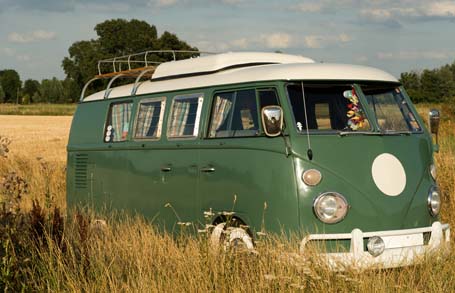 Das Bild zeigt einen alten VW-Bus in einem Feld.